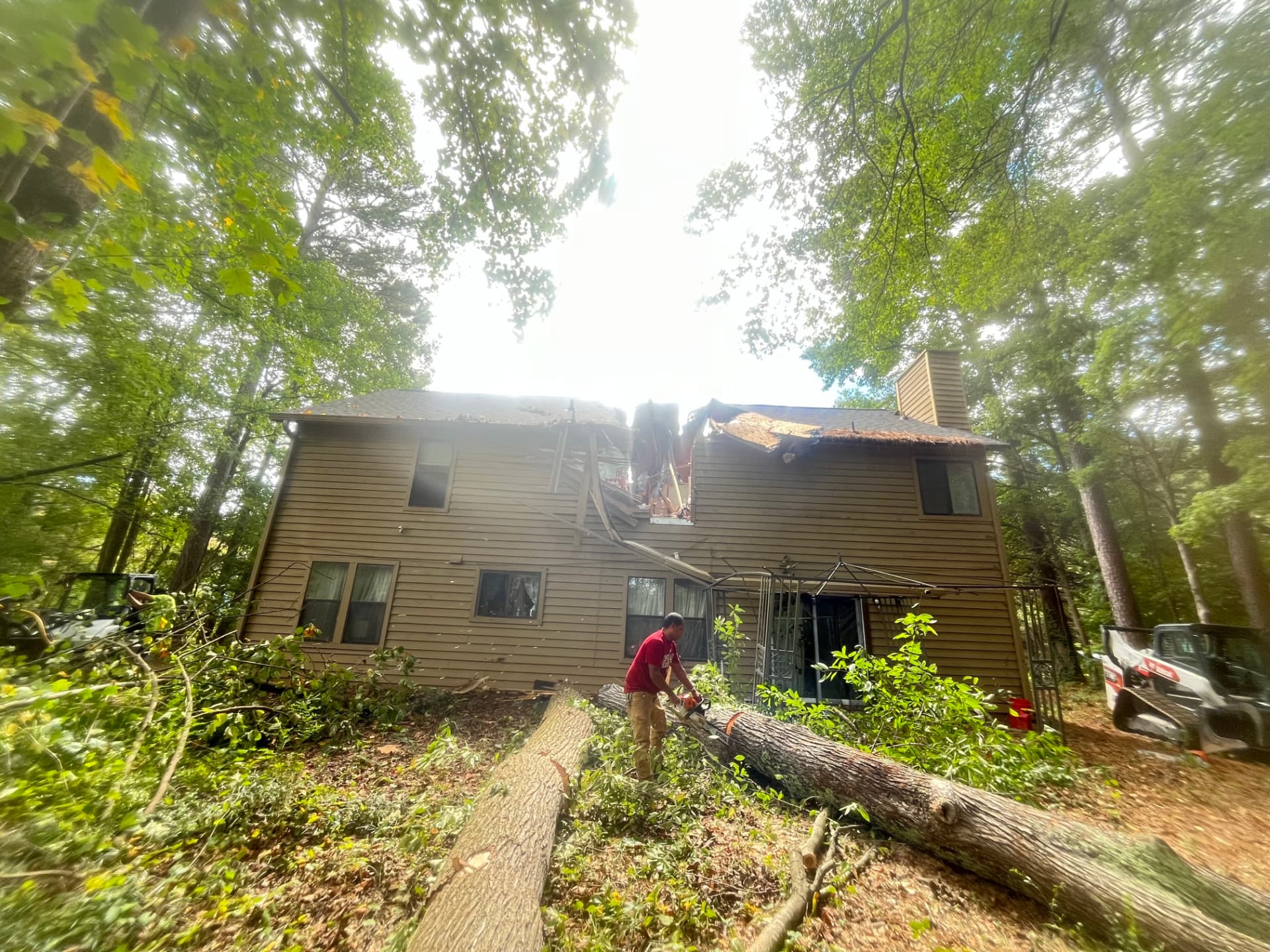 Crew clearing a fallen tree that crashed through the roof of a two-story home